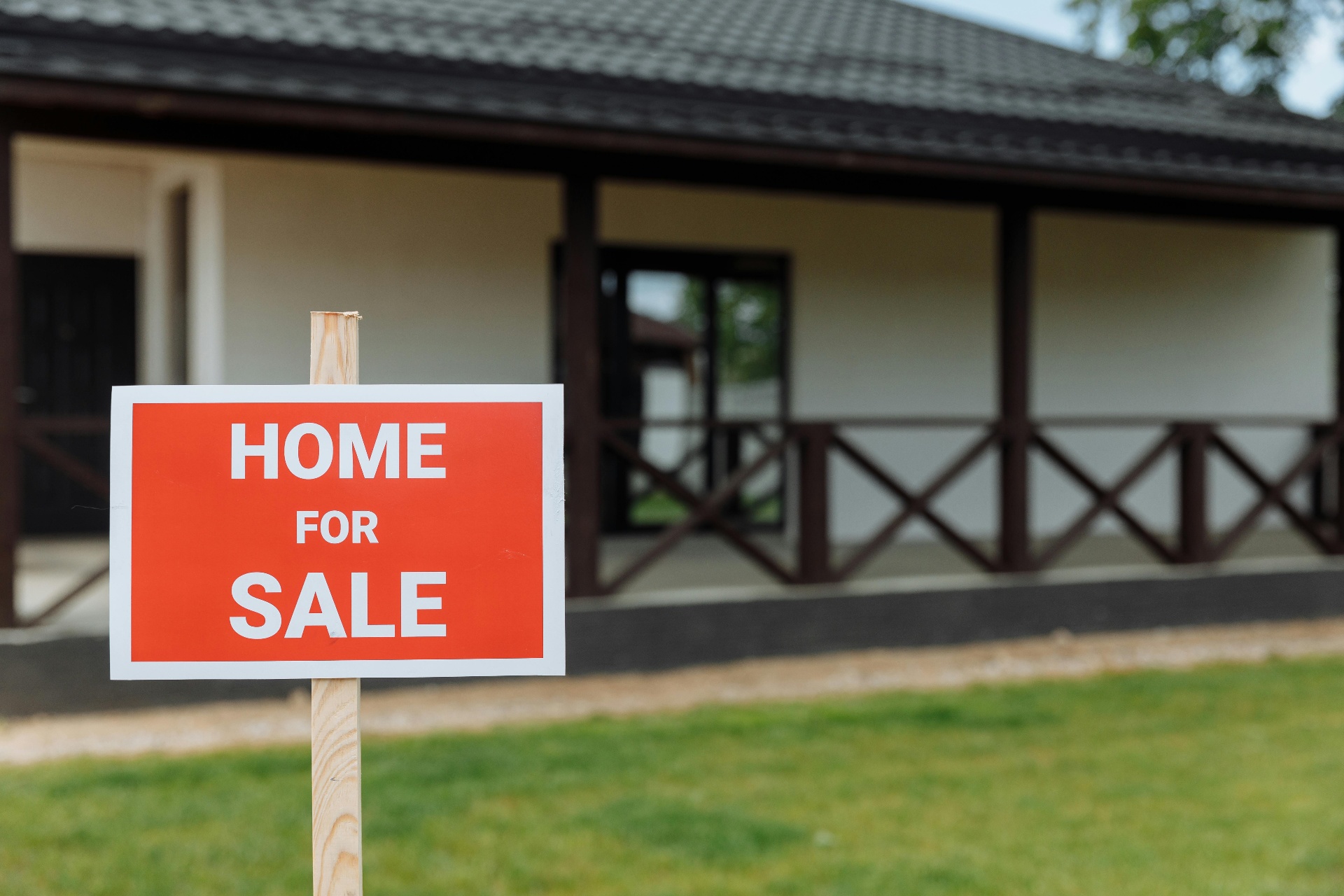 Home for sale sign in front of a beautiful property with covered porch